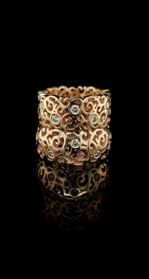 Gouden ring met opengewerkt krulwerk en ingezette diamanten.