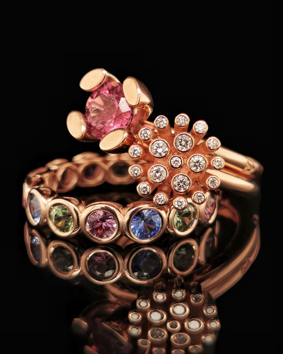 Ring met een roze saffier naast een bloem van briljanten, op een band met gekleurde saffieren.